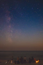 A small group of people gathered around a telescope under a clear starry night sky.