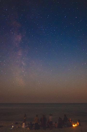 A diverse group of people collaborating on futuristic projects under a starry sky.