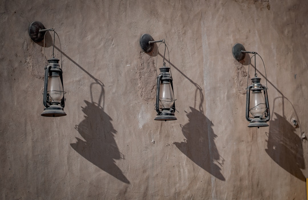 three oil lanterns hanging on brown wall