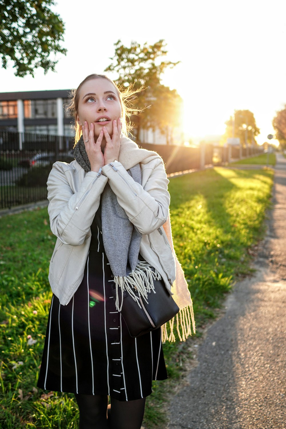 woman in grey coat standing in pavement outdoors during daytime