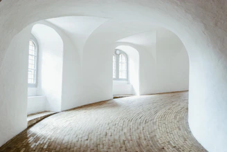 A serene architectural space bathed in soft natural light, featuring stone and wood textures.