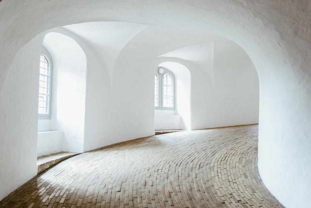 a room with a brick floor and arched windows