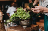 Artisan florist arranging stabilized flowers in a cream and sage toned workshop