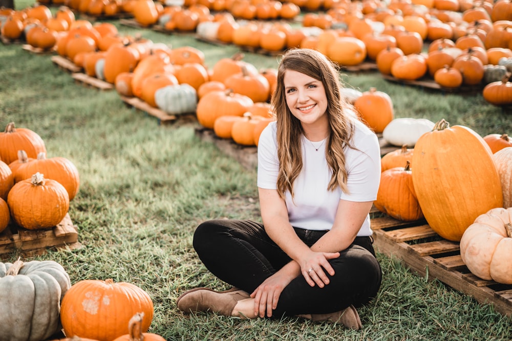 woman sitting next to pumpkins