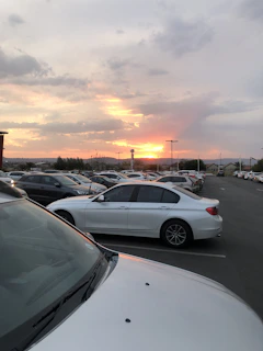 A panoramic shot of several used cars lined up neatly in the 3l_auto lot at sunset