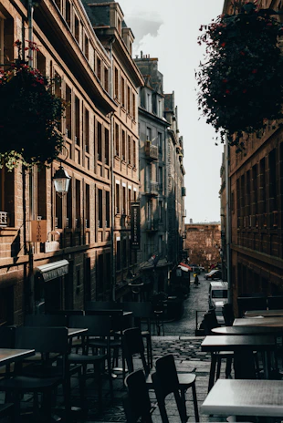 A cobblestone street lined with historic buildings and quaint cafes under soft afternoon light.