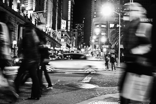 A dynamic black-and-white photo of a bustling city street at dusk with blurred motion of pedestrians.