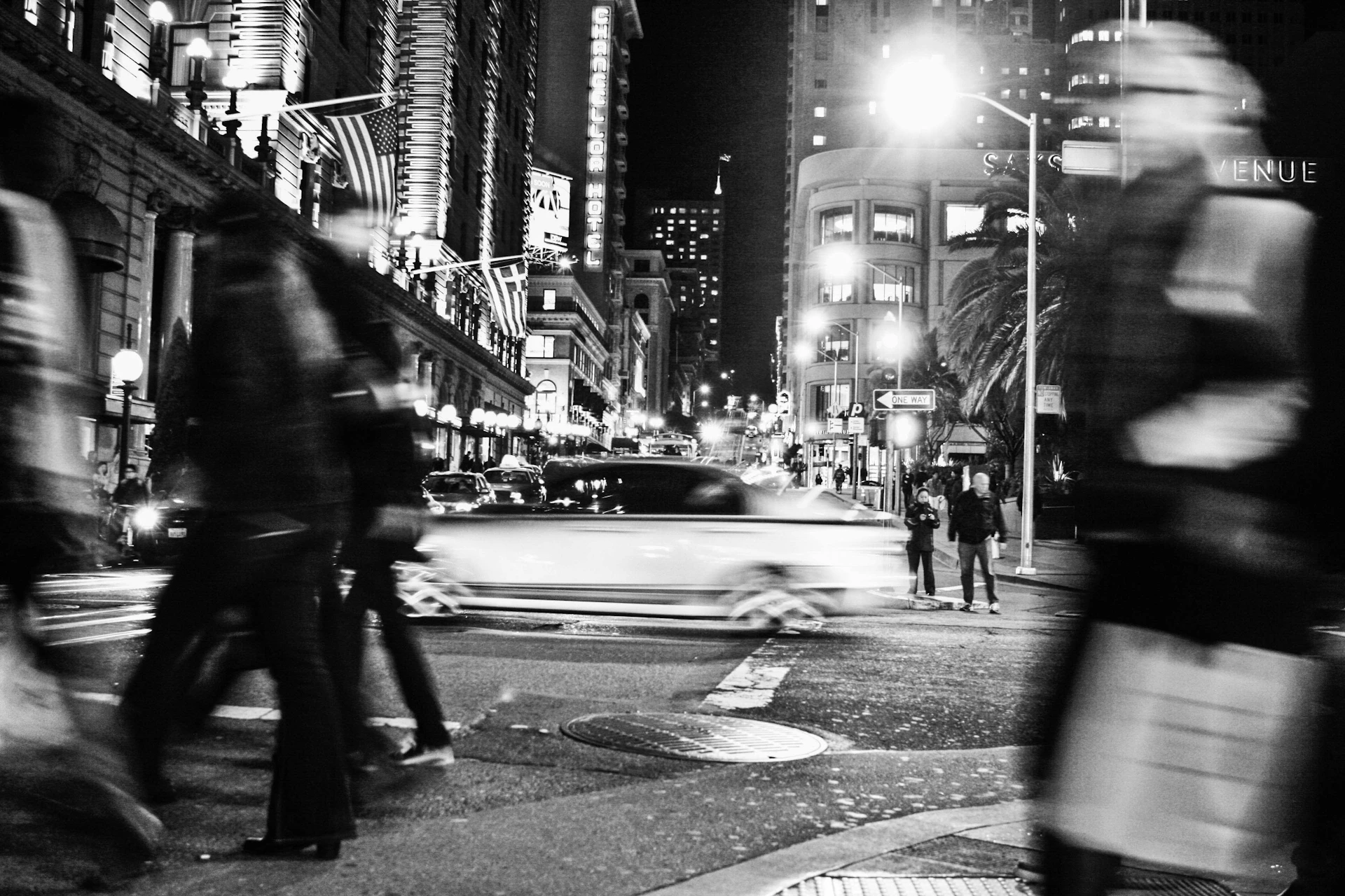 A candid moment of a city street at night, with blurred lights and people walking, reflecting the pulse of urban adventure.