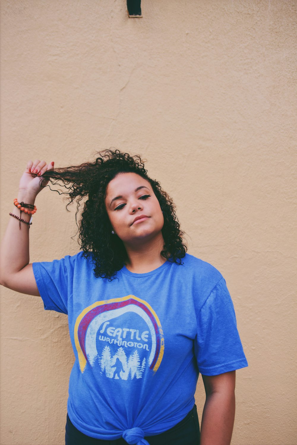 woman wearing blue shirt standing near white wall