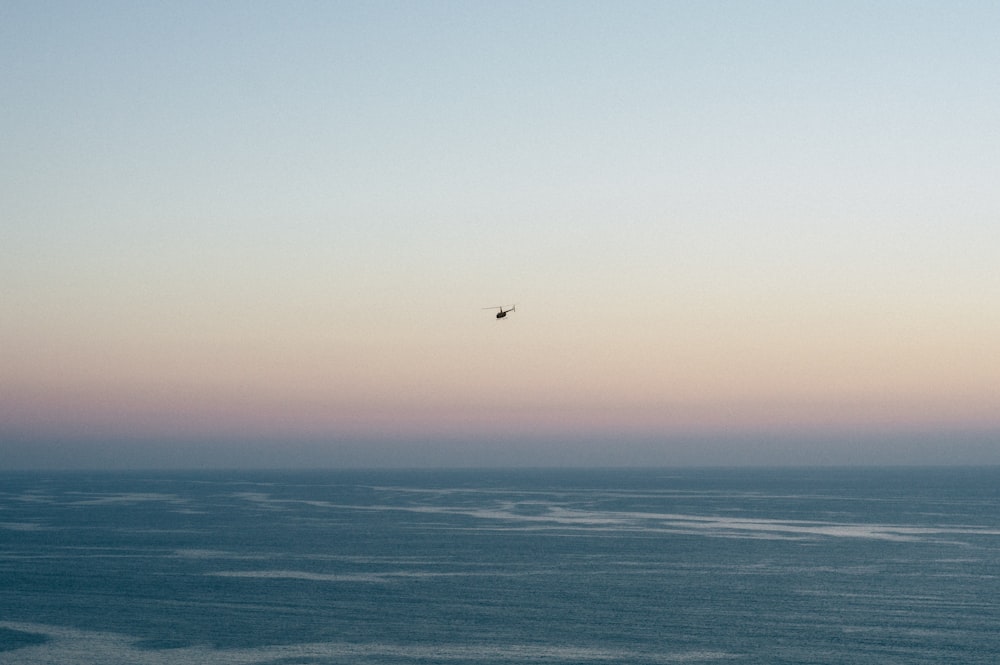 photo of helicopter hovering above body of water