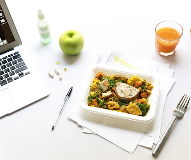 vegetables on plate beside fork and laptop