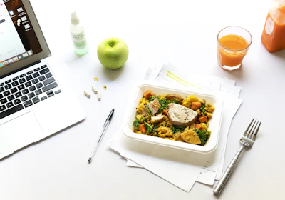 vegetables on plate beside fork and laptop
