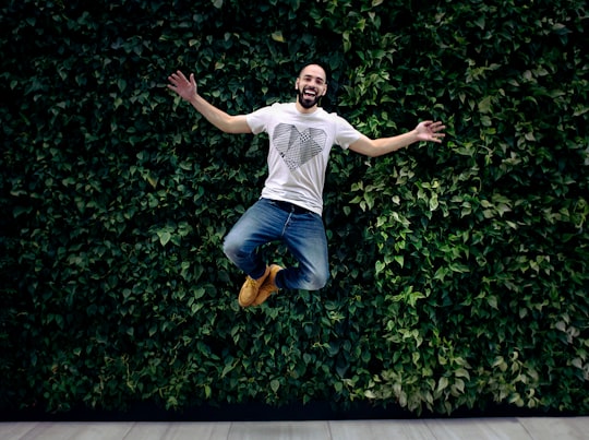 man wearing t-shirt and jeans jumpshot in front of a green hedge in Dunwoody United States