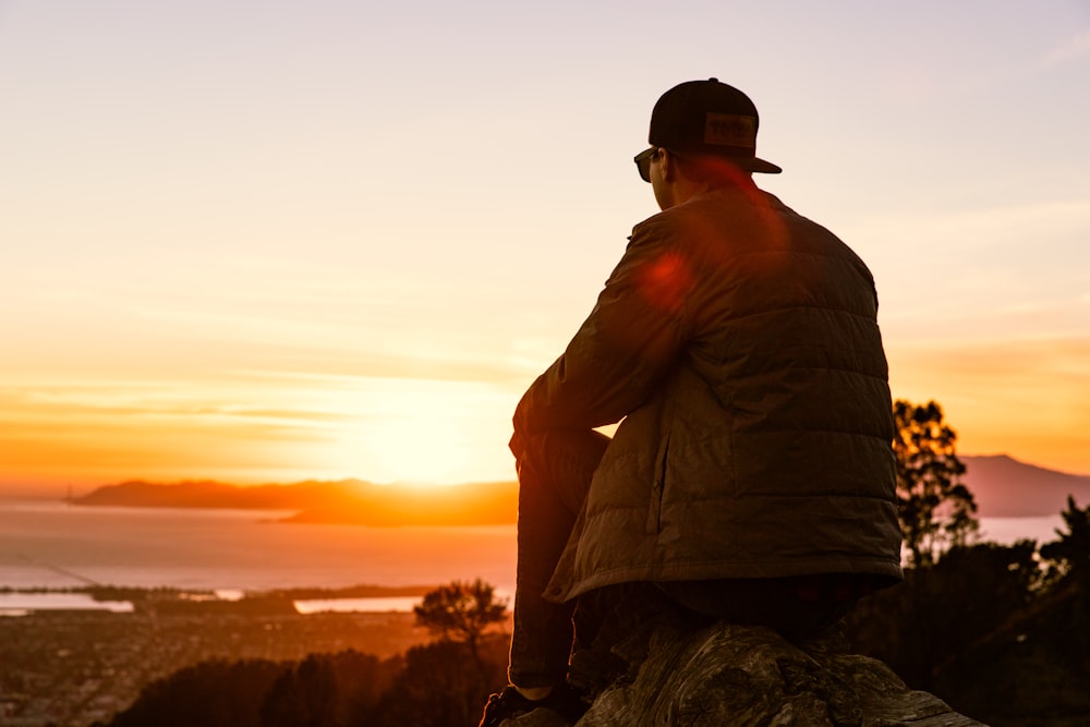 man sitting on rock looking at sunrise