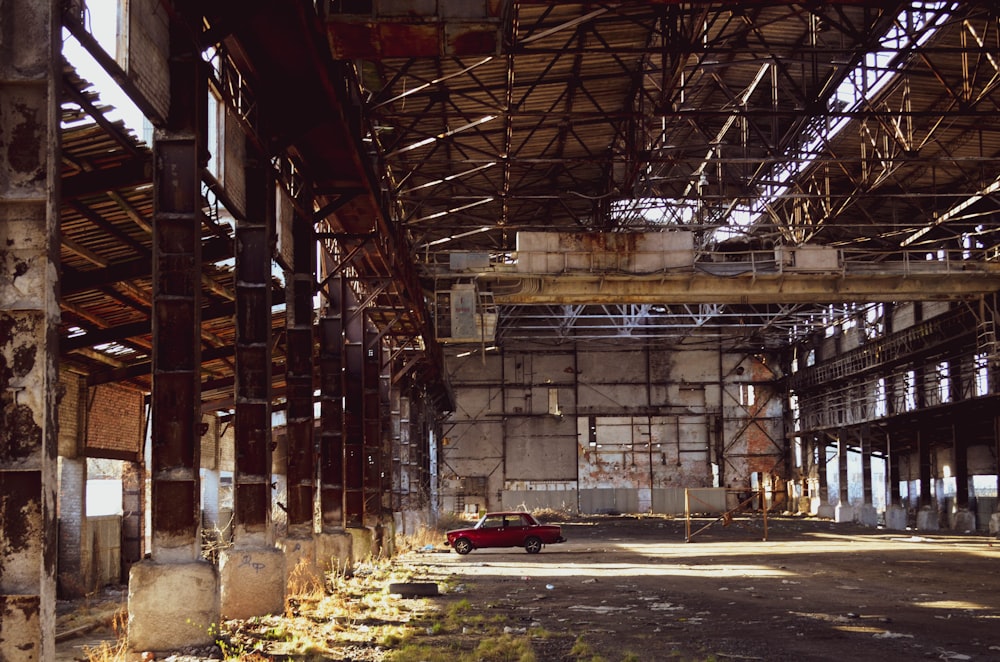 red car in abandoned warehouse during daytime