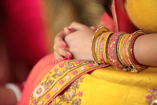 person wearing yellow sari dress holding both hands