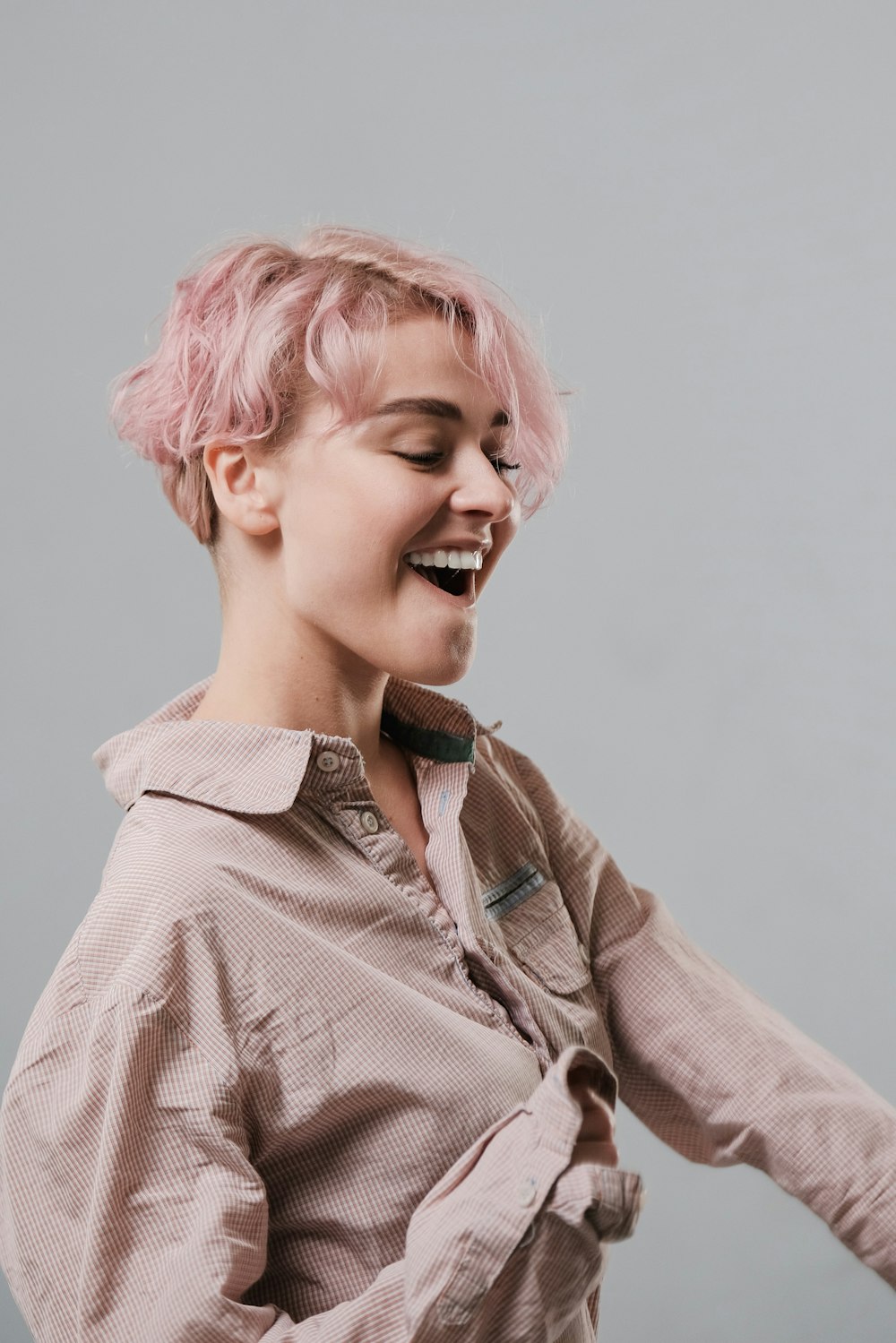 woman with pink short hair wearing beige dress shirt