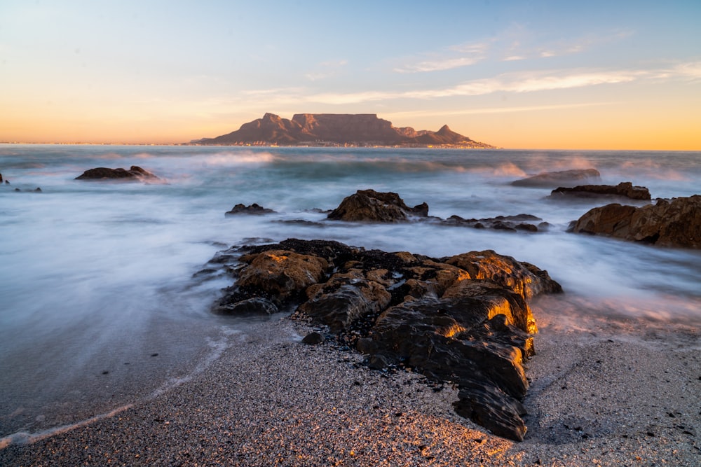 water splashing on shore rocks overlooking island at the horizon