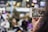 A person holding a smartphone taking a video of a group of people dancing in an outdoor, urban setting. The background appears blurred with bokeh lights, indicating a lively environment.