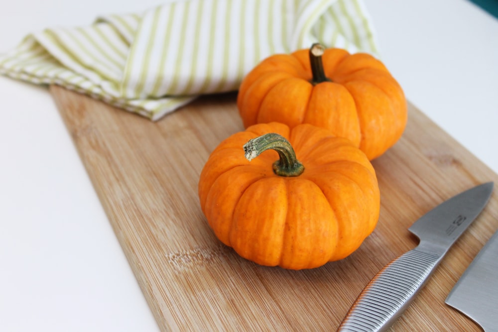 selective focus photography of two pumpkins placed on chopping board