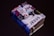 A small, thick book covered with various colorful stickers and texts, prominently featuring the word 'JESUS'. It is set against a plain dark background, enhancing the contrast of the vibrant collage on the book cover.