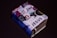 A small, thick book covered with various colorful stickers and texts, prominently featuring the word 'JESUS'. It is set against a plain dark background, enhancing the contrast of the vibrant collage on the book cover.