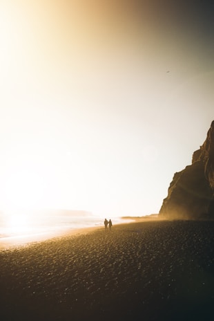 Sunset stroll of a couple laughing together along a beachfront promenade.