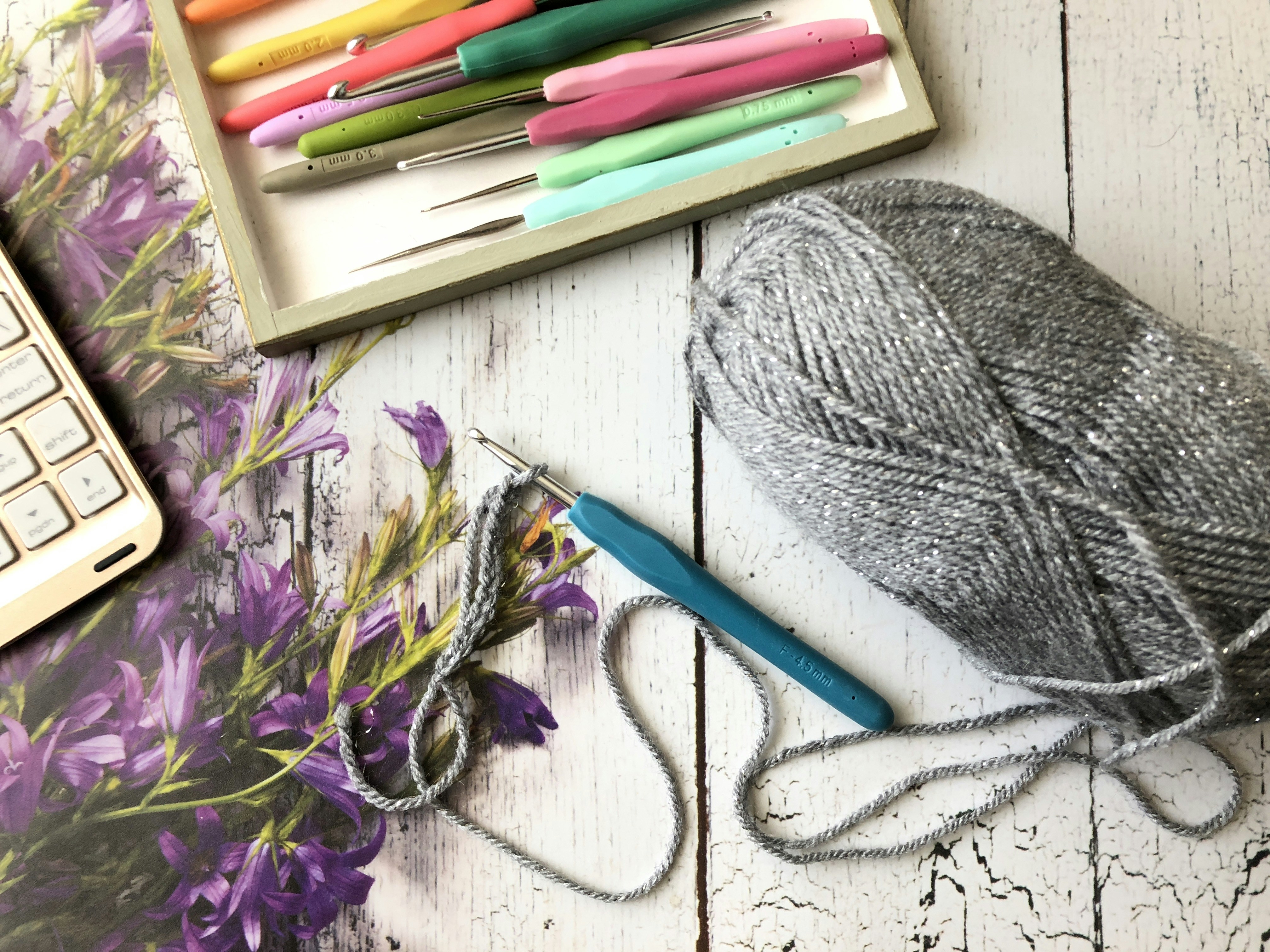 Crochet sun hat on wooden surface with summer flowers