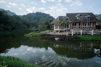 A serene wetland landscape with a lightweight, open-structured home blending seamlessly into the natural surroundings under a soft, cloudy sky.