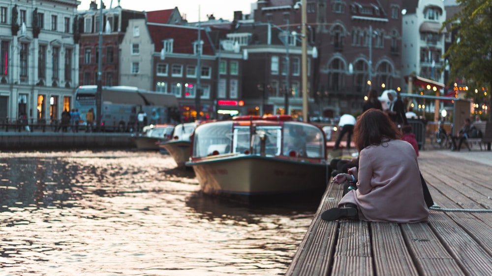 woman sitting on dock near boat