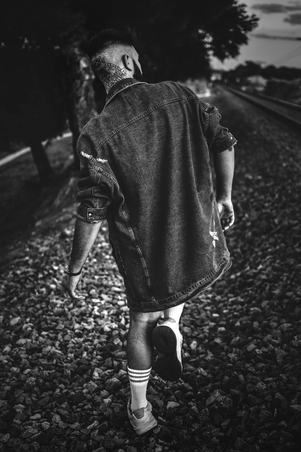 a man walking down a train track next to a forest