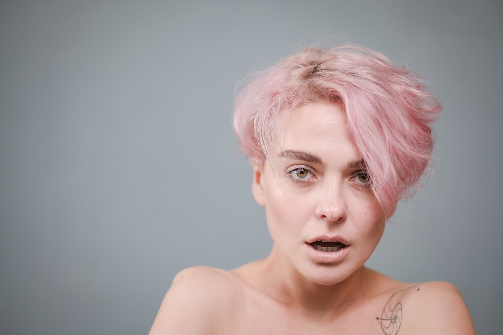 a woman with pink hair has a surprised look on her face