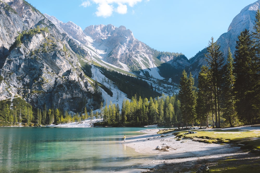 person standing by the glassy lake at mountain side