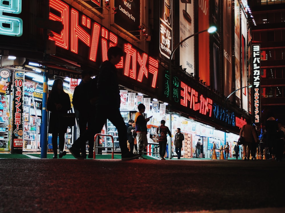 people walking by lighted buildings at night