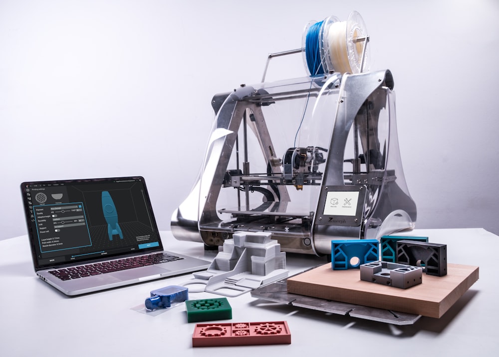 turned-on MacBook on table beside gray industrial machine