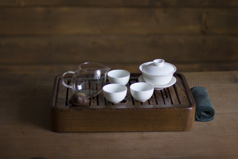 white ceramic bowls and clear glass pitcher on brown wooden tray