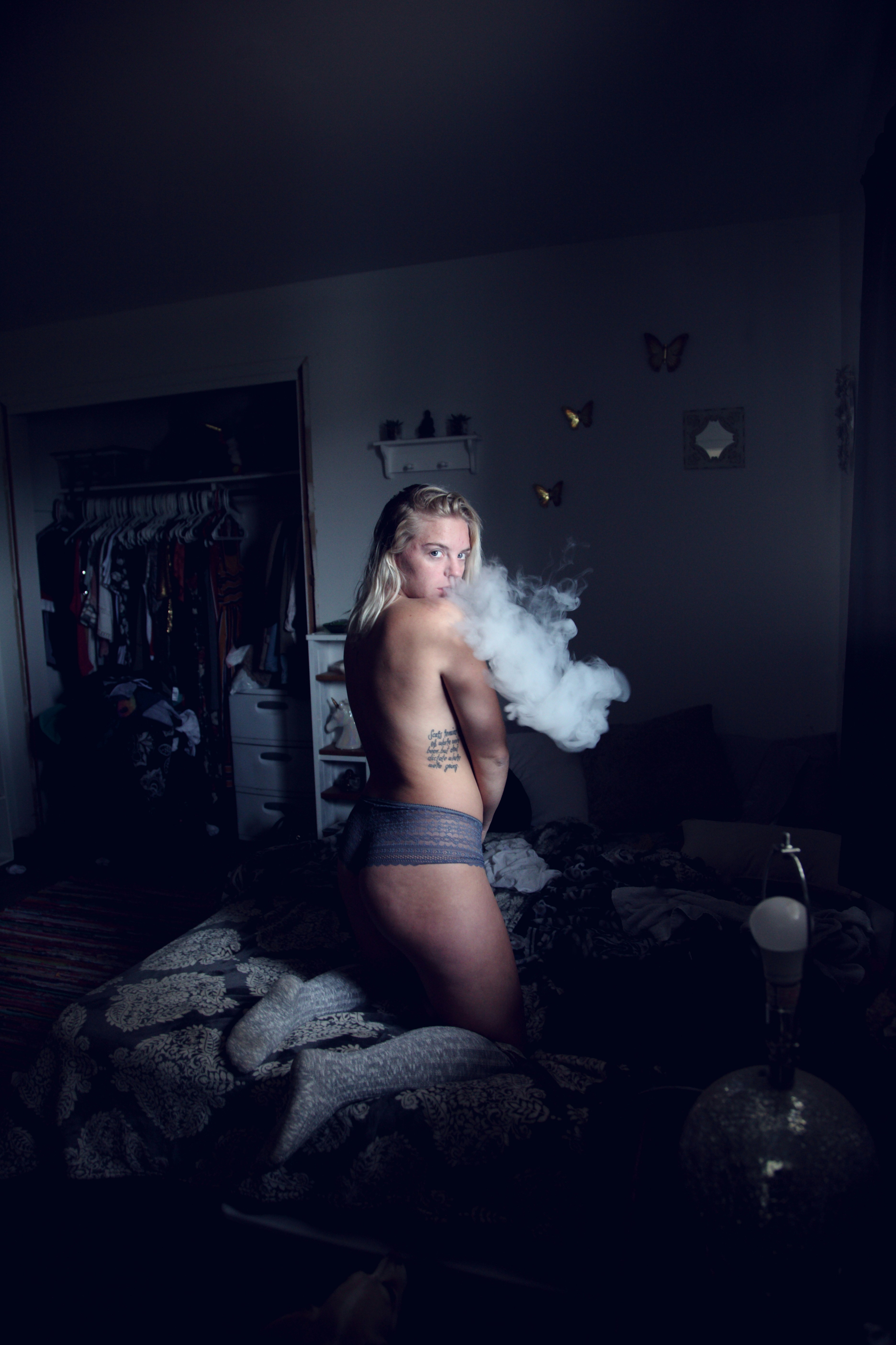 A twenty-five year old woman vaping in her bedroom in natural Northern window light.