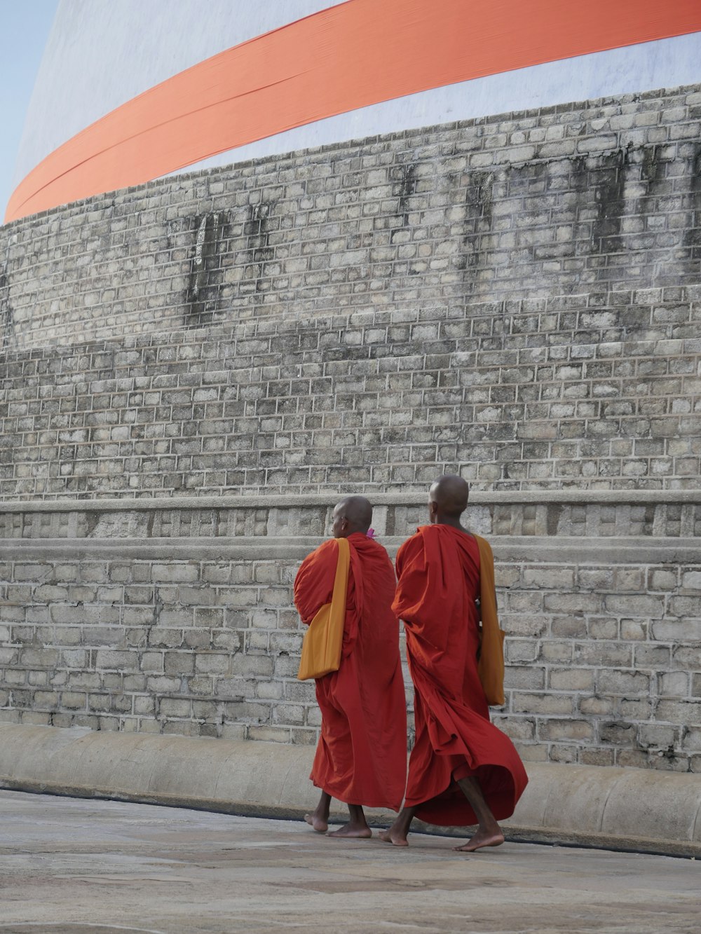 two man walking beside concrete wall