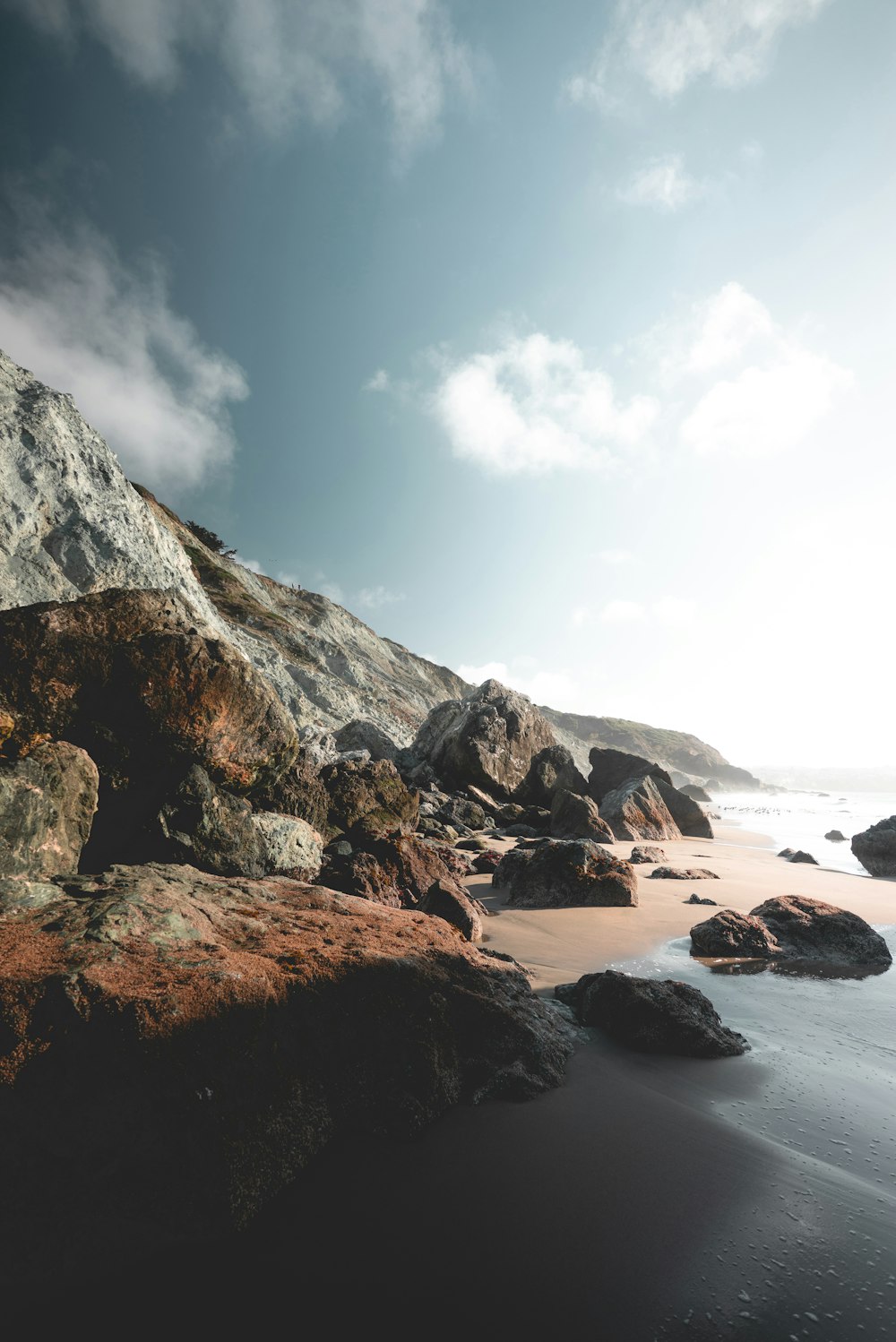 a beach with rocks and water under a cloudy sky