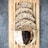 Five slices of rustic sourdough bread are placed on a wooden cutting board. The bread has a crusty exterior with a slightly burnt section and a porous, airy interior. The background features a textured, gray stone surface.