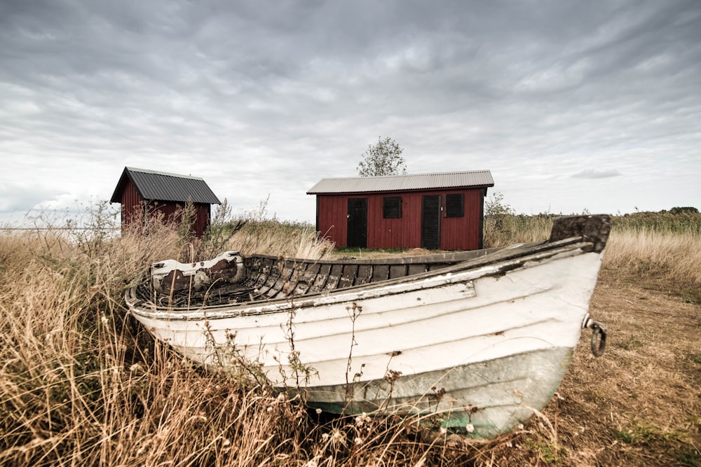 white wooden boat near shed