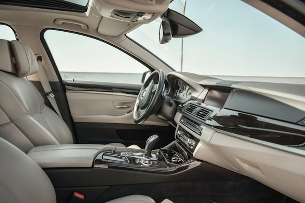 A cozy car interior with a sleek dining table set up, a subtle car perfume bottle on the dashboard, and soft natural light streaming through the windows.