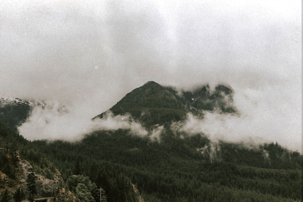 a black and white photo of a mountain covered in clouds