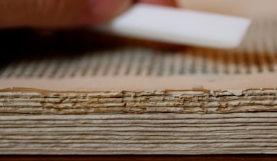 An ancient book being carefully restored with delicate tools on a wooden table.