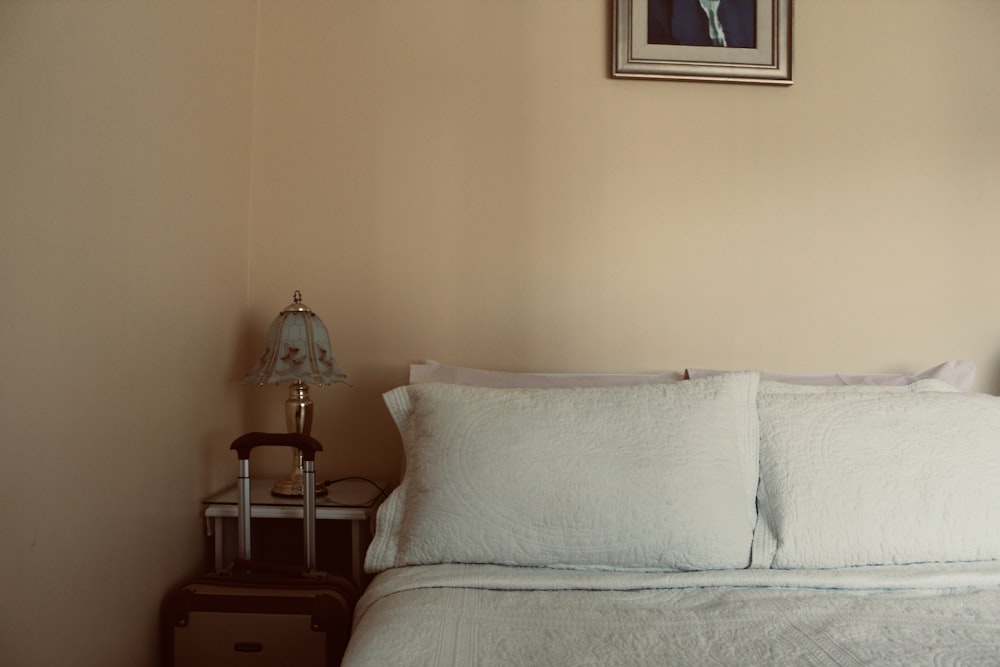 white bed beside wooden nightstand inside room