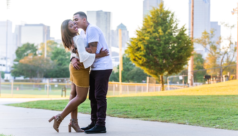 man kissing woman's cheek during daytime