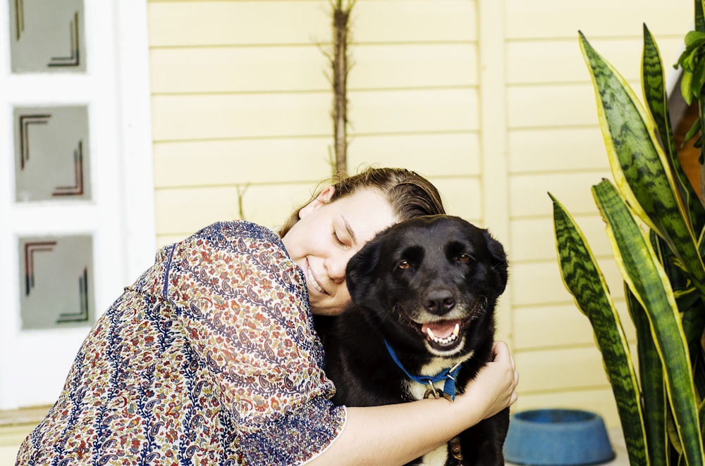 woman hugging black dog