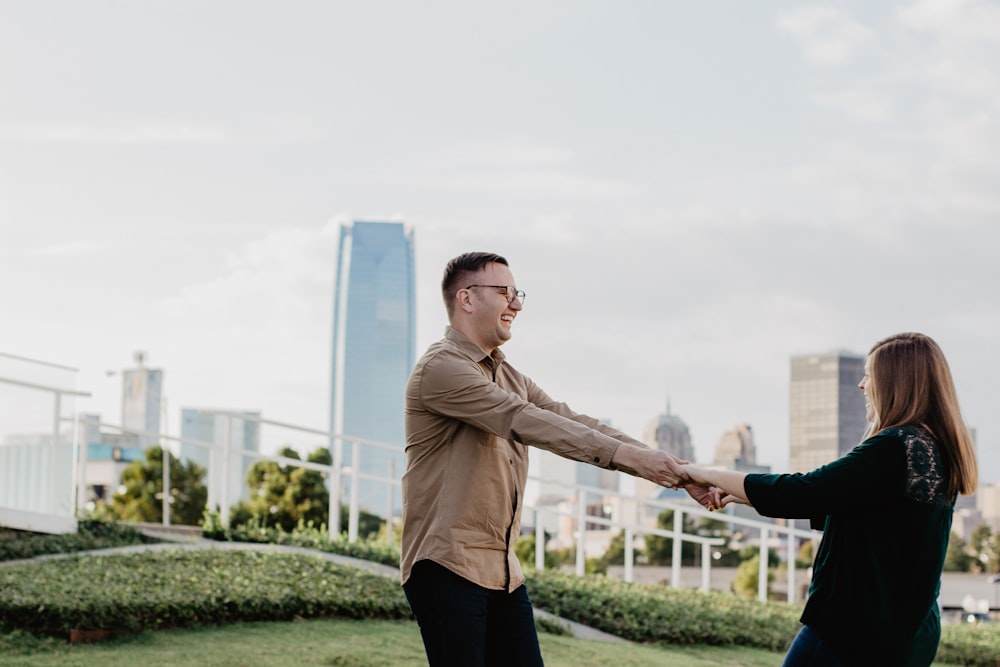 woman and man holding hands on grass field