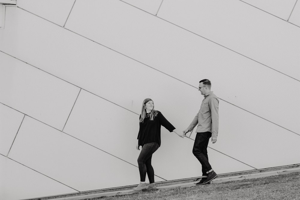 grayscale photo of woman holding hand of man