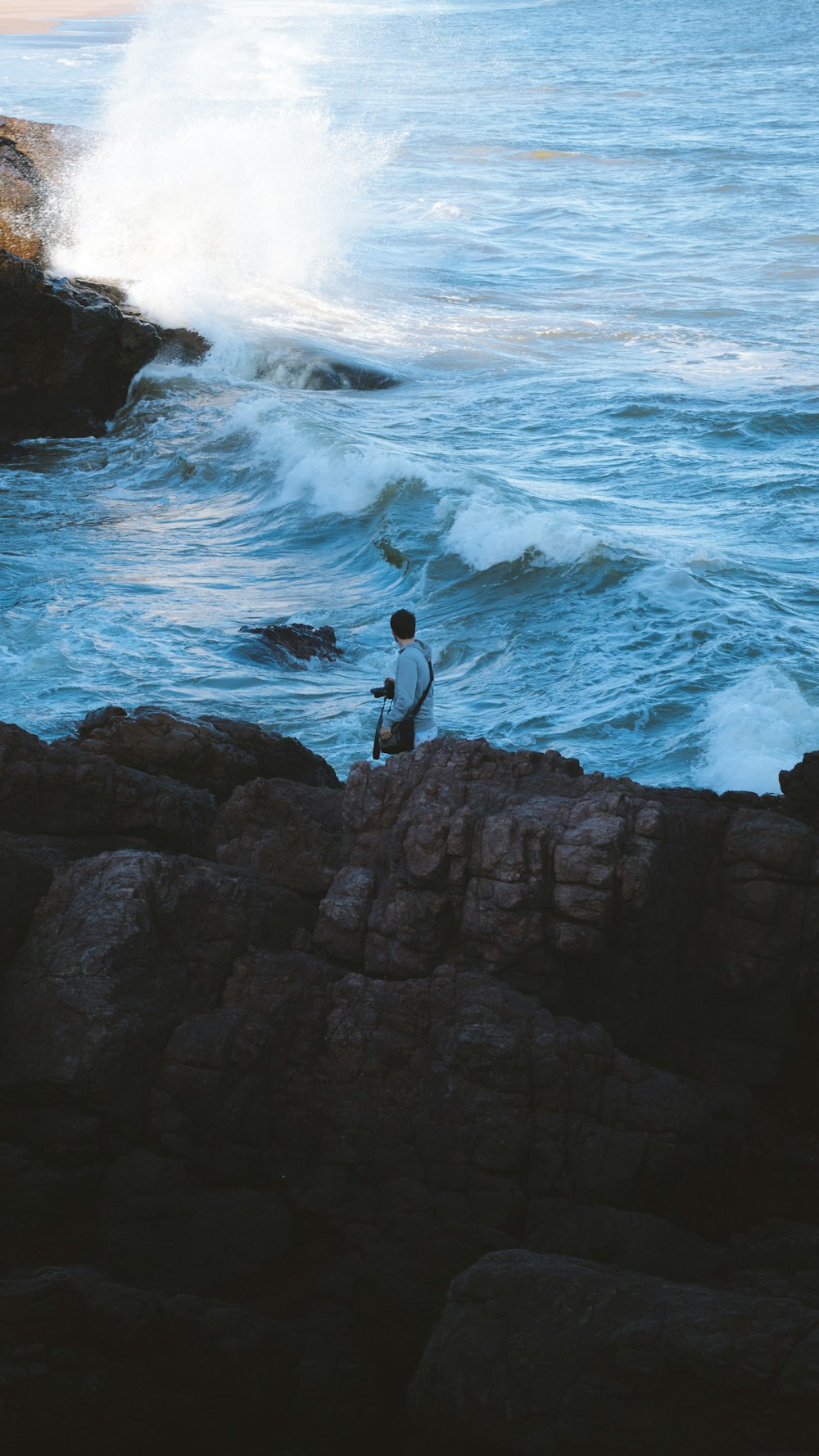 海の隣の岩の上に座っている男
